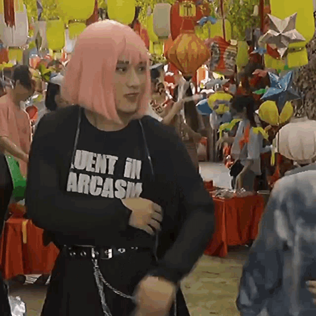 a woman in a pink wig is wearing a black shirt that says uent in arcash