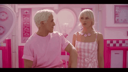 a man in a pink shirt and a woman in a pink dress are standing next to each other in a pink room