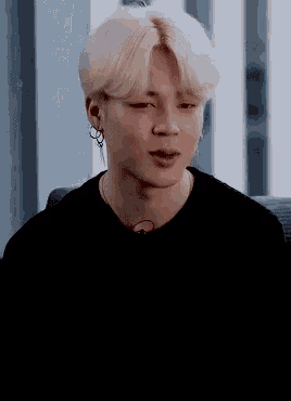 a close up of a person wearing a black shirt and earrings