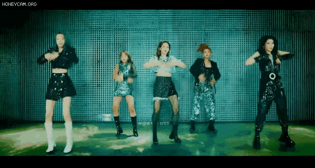 a group of young women are dancing in front of a wall .