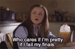 a girl is sitting at a table and says who cares if i 'm pretty if i fail my finals ..