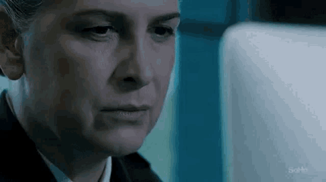 a woman in a suit and tie is looking at a computer screen .
