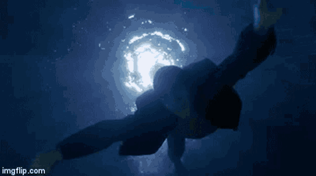 a man in a suit is swimming underwater in a pool
