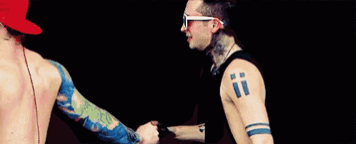 two men are shaking hands and one has a tattoo on his arm that says ii .