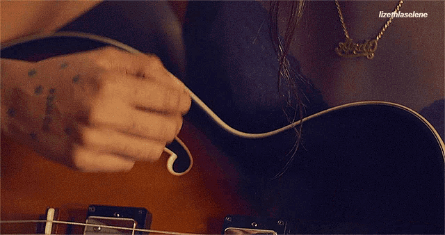 a close up of a guitar with lizethlaselene written in the corner