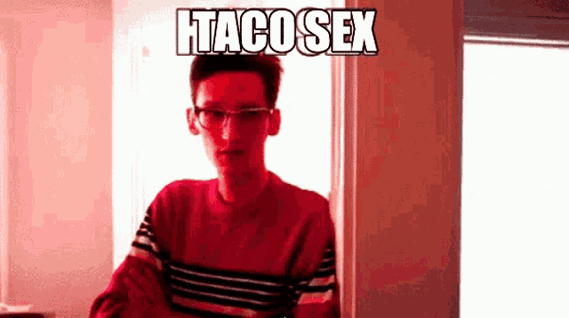 a man wearing glasses and a red sweater stands in front of a sign that says " htaco sex "