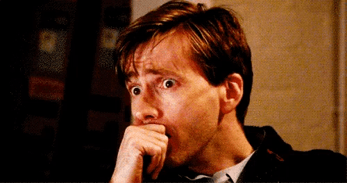 a man is covering his mouth with his hand and looking at the camera .