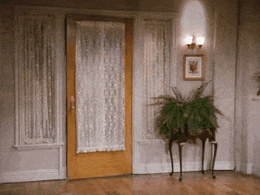 a room with a plant on a table and a picture on the wall above it