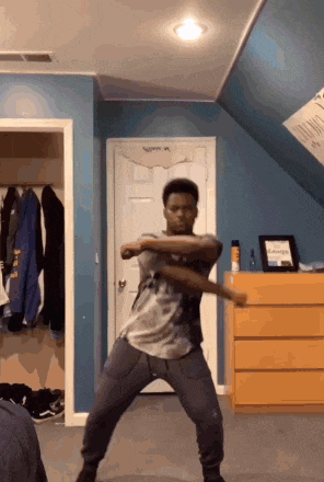 a young man is dancing in a room with blue walls and a dresser with a picture on it