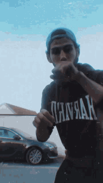 a man wearing a shirt that says ' havana ' on it stands in front of a car
