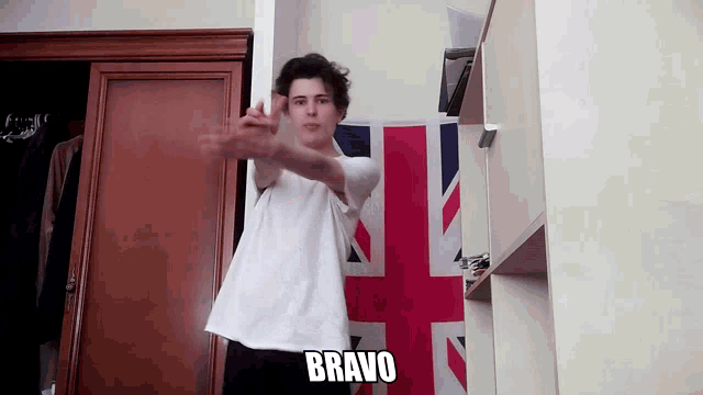 a man in a white shirt is standing in front of a british flag with the word bravo written on it