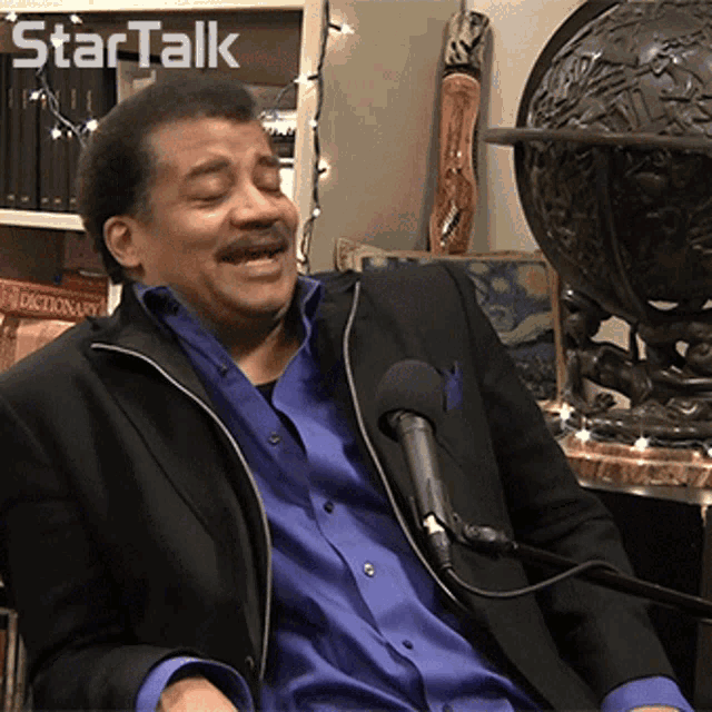 a man in a suit is sitting in front of a microphone with the words star talk behind him