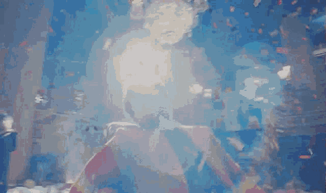 a woman in a red dress is standing in front of a chandelier surrounded by confetti .