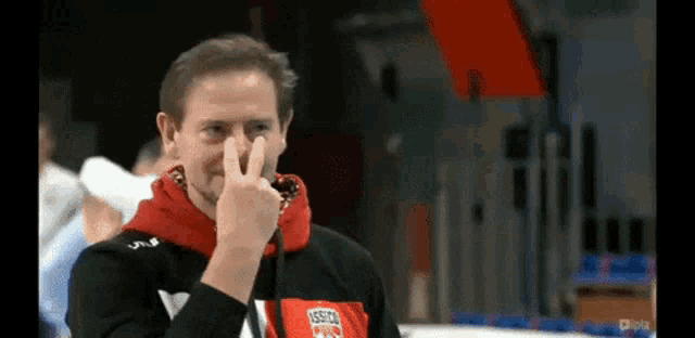a man covering his nose with his fingers and a shirt that says ' hessen pro ' on it