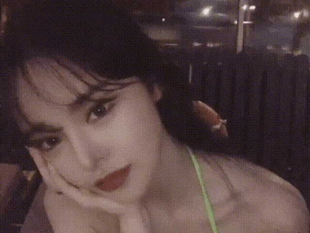 a woman in a green bikini is sitting in a chair with her hand on her chin .