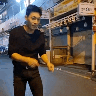 a man in a black shirt and black pants is walking down a street .