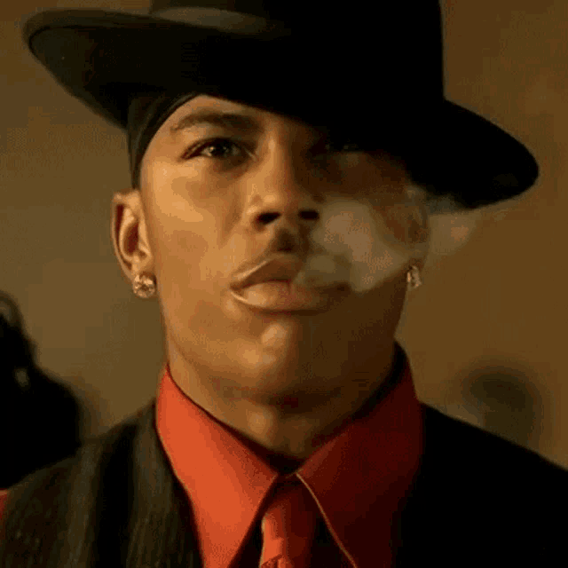 a man wearing a top hat and a red shirt is smoking a cigarette .