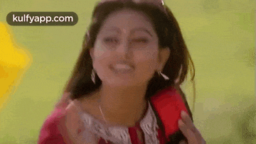 a woman is talking on a red cell phone while smiling .