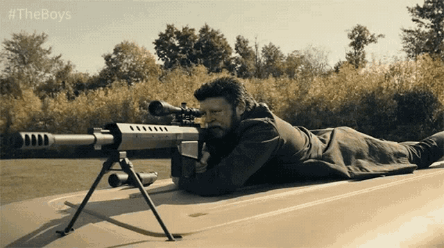 a man with a sniper rifle is laying on the roof of a car with #theboys written on the bottom