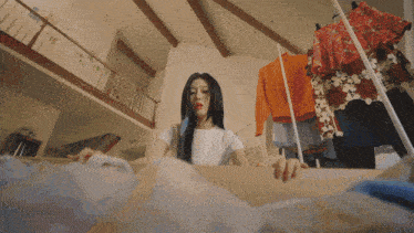 a woman in a white shirt is looking at clothes