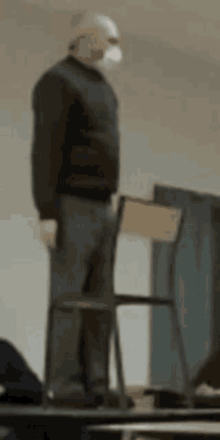 a man in a mask is standing on a chair .