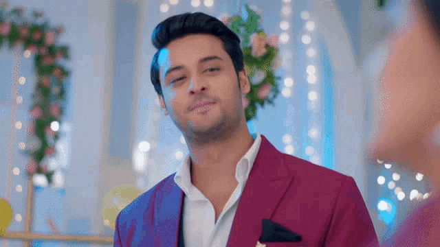 a man wearing a purple suit and white shirt smiles