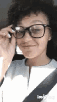 a woman wearing glasses is sitting in a car with a seat belt .