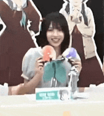 a woman is sitting at a table holding a donut in front of a group of anime characters .