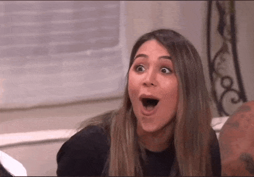 a woman is sitting on a couch with her mouth open and making a funny face .