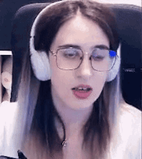 a woman wearing headphones and glasses is looking at the camera .