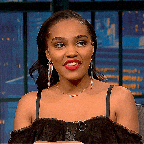 a woman wearing a necklace and earrings is smiling for the camera