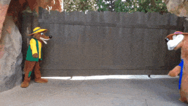two stuffed animals are standing next to a wooden fence