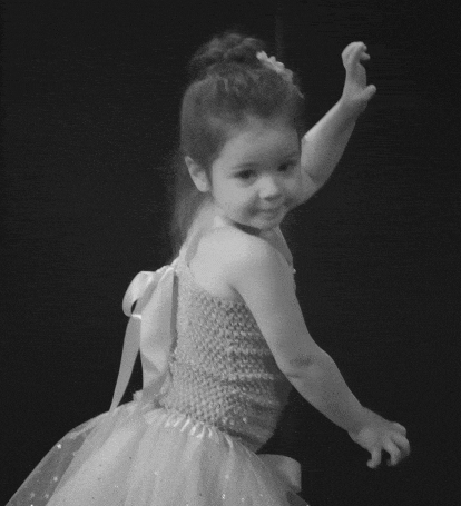 a little girl in a dress with a bow on the back is dancing