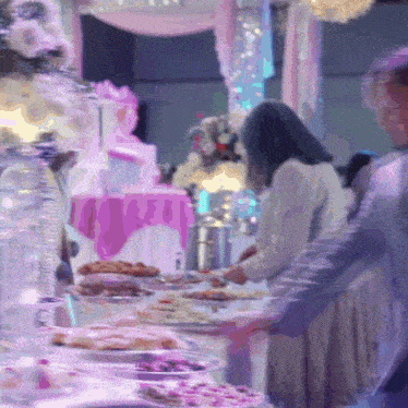 a blurry picture of people standing around a table with food