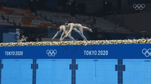 a woman is diving into a pool with tokyo 2020 written on the side