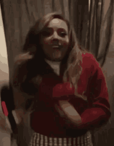 a woman in a red sweater is holding a bottle of wine and dancing in a room .