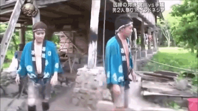 two men wearing blue kimonos are walking in front of a building