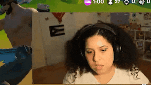 a woman wearing headphones is playing a video game while a man stands in the background