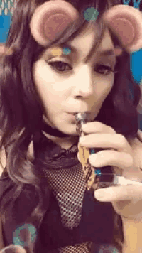 a woman is smoking an electronic cigarette with a filter on her face .