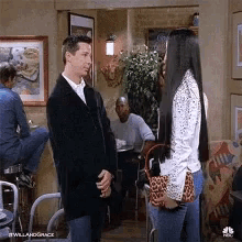 a man in a suit and a woman in a white shirt are talking in a restaurant .