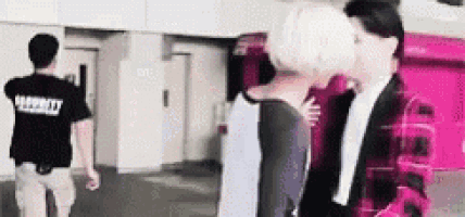 a man and a woman are kissing in a room while a man watches .