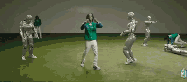 a man in a green jacket is surrounded by silver robots and a carton of lemonade