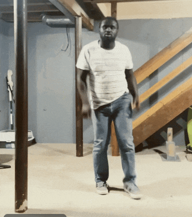 a man in a striped shirt and jeans is standing in a basement