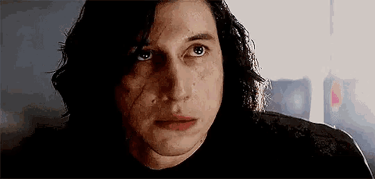 a close up of a man 's face with long hair and a black shirt .