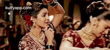 a woman in a red and gold dress is dancing in a crowd .