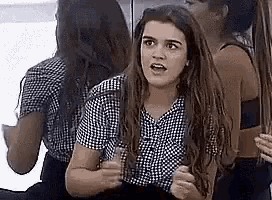 a woman with long hair is sitting in front of a mirror making a funny face .