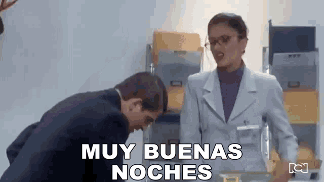 a man in a suit and a woman in a purple sweater are standing next to each other in an office .