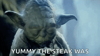 a close up of a statue of yoda eating a steak and saying `` yummy the steak was '' .