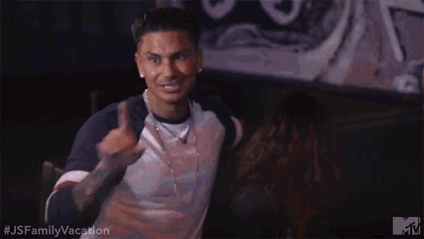 a man is giving a thumbs up while talking to a woman in a dark room .
