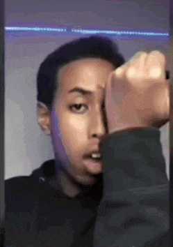 a young man is taking a picture of himself in a mirror with his fist in the air .